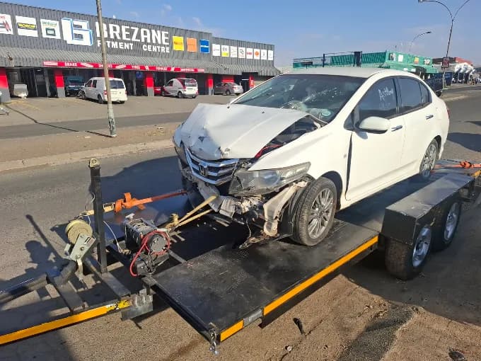 ASD Towing recovering an accident-damaged white vehicle on a trailer